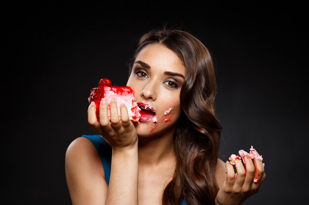 Cheerful woman in blue dress eating piece of cake