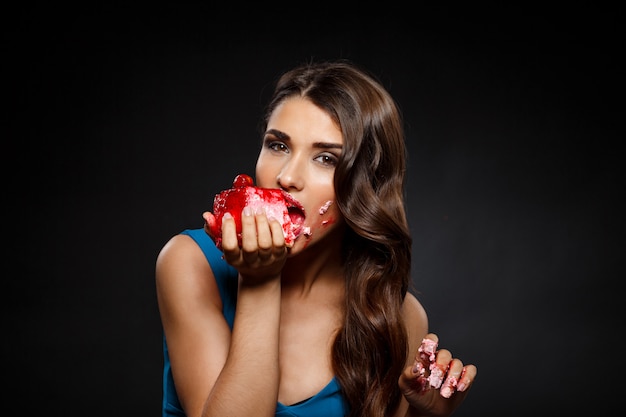 Free photo cheerful woman in blue dress eating piece of cake