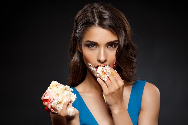 Жизнерадостная женщина в голубом платье ест кусок пирога