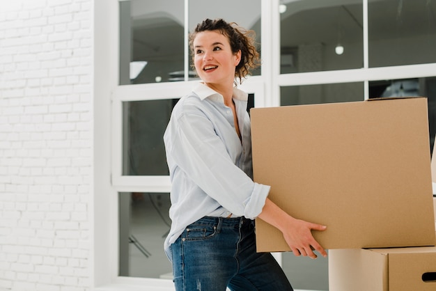 Free photo cheerful woman carrying box