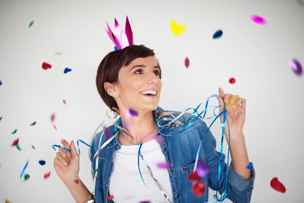 Cheerful woman dancing among colorful confetti pieces
