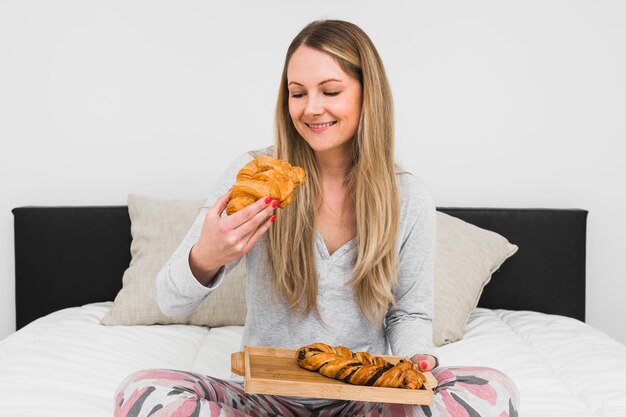 ベッドでパンを食べる陽気な女性