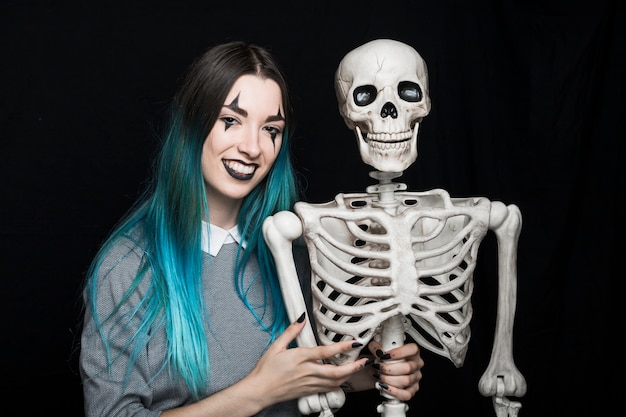 Cheerful woman embracing skeleton