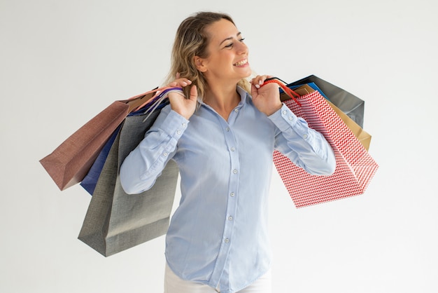 Cheerful woman enjoying shopping and carrying many bags