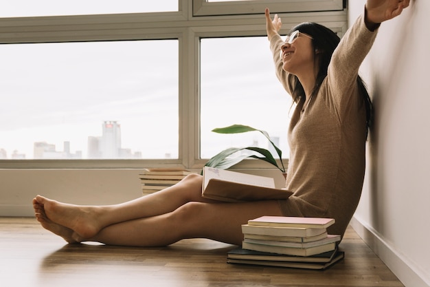 Cheerful woman in glasses reading on floor