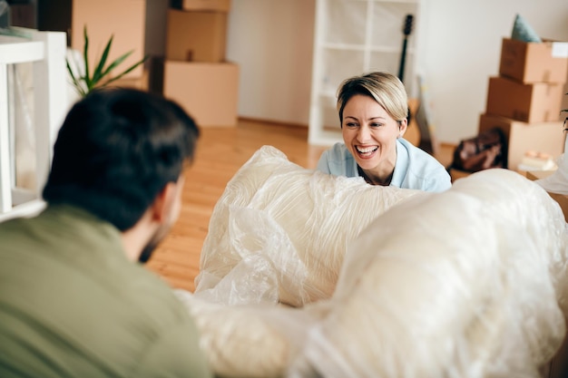 Cheerful woman having fun with her husband while moving into new apartment