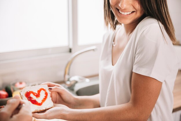 Cheerful woman holding breakfast toast with jam