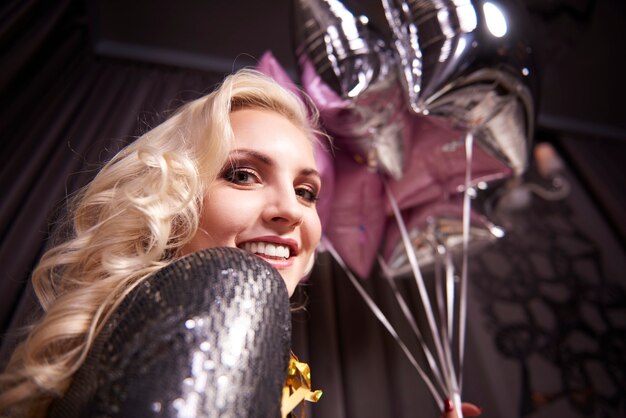 Cheerful woman holding bunch of balloon at night club