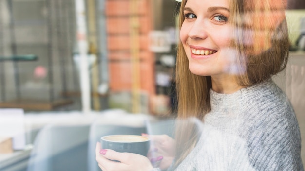 コーヒーのカップを持っている陽気な女性