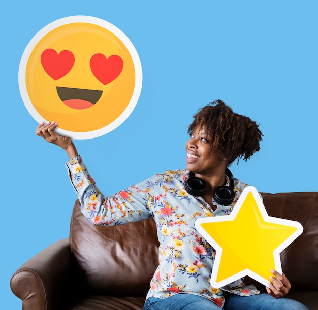 Cheerful woman holding a heart eyes emoticon and star icons