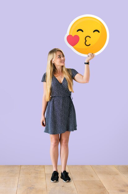 Cheerful woman holding a kissing emoticon