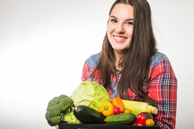 Веселая женщина, держащая поддон с овощами