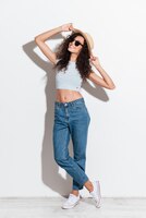 cheerful woman in jeans hat and sunglasses smiling to camera