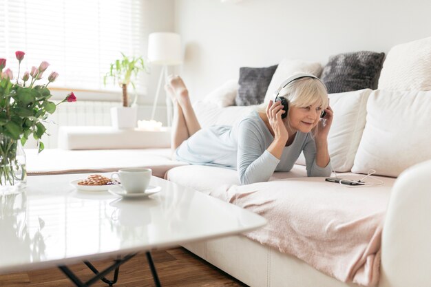 Cheerful woman listening to music on couch