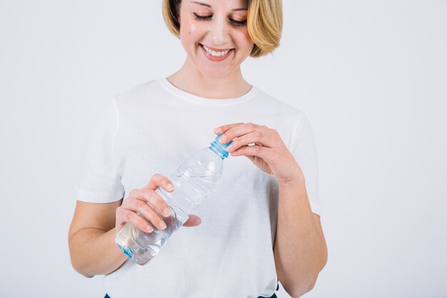 Cheerful woman opening bottle on white background