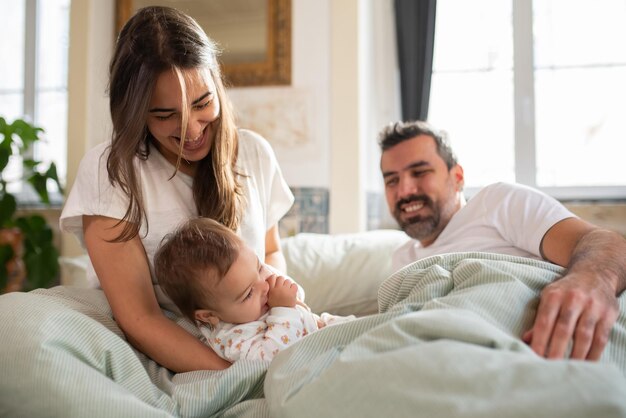 Cheerful woman playing with her baby son in bed