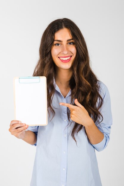 Cheerful woman pointing at clipboard