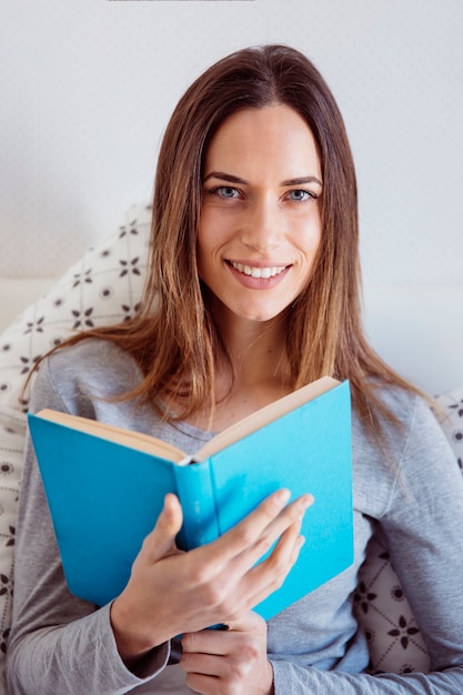 ベッドで読書する朗らかな女性