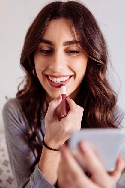 Cheerful woman rouging lips