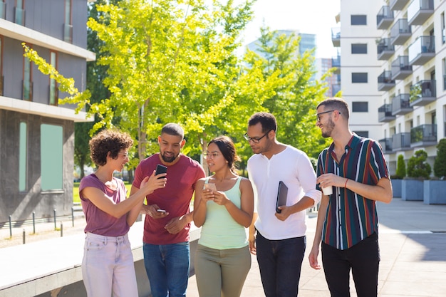 Cheerful woman showing phone screen to her excited peers