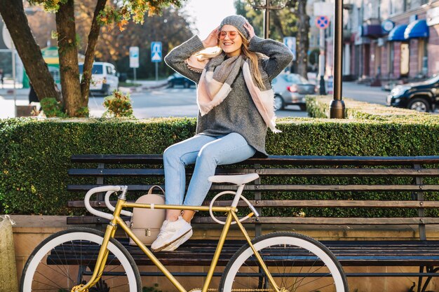 Cheerful woman sitting on bench near bicycle