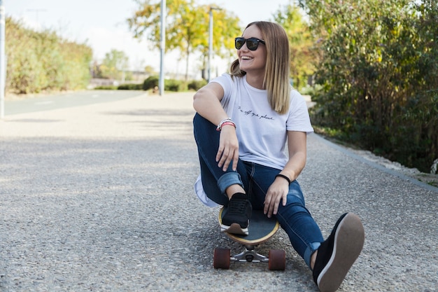 Cheerful woman sitting on longboard