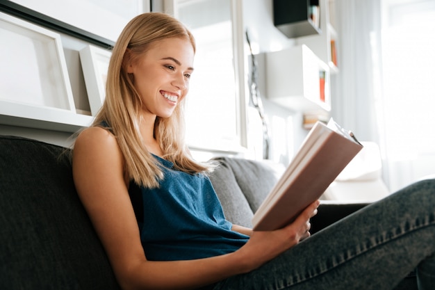 ソファーに座って本を読んで陽気な女性