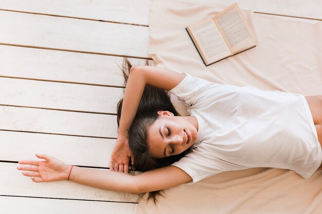 Cheerful woman sleeping near book