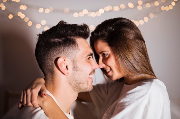 Cheerful woman and smiling man hugging in dark room