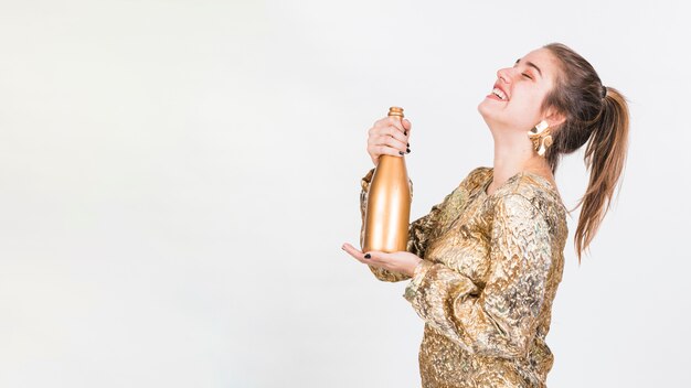 Cheerful woman standing with bottle of champagne