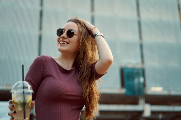 Cheerful woman in the street drinking morning refreshing drink