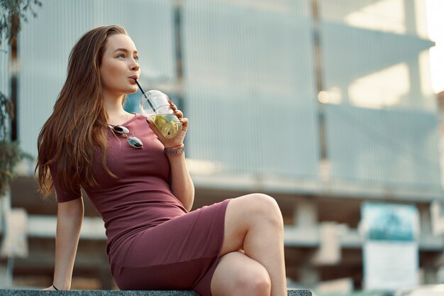 Cheerful woman in the street drinking morning refreshing drink