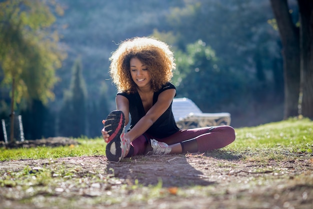 Cheerful woman stretching her leg on the ground