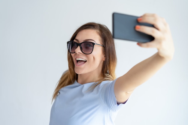 Cheerful woman taking selfie photo on smartphone