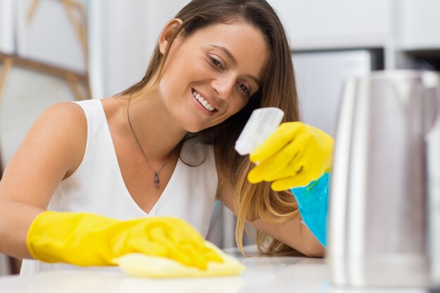 Cheerful woman thoroughly wiping table