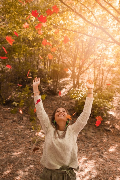 Веселая женщина бросает осенние листья