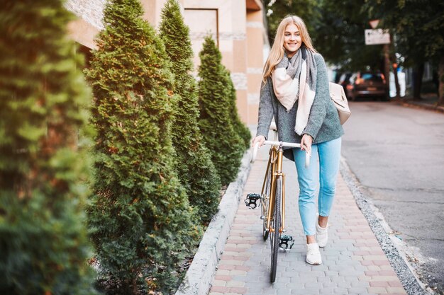 Веселая женщина, идущая с велосипедом