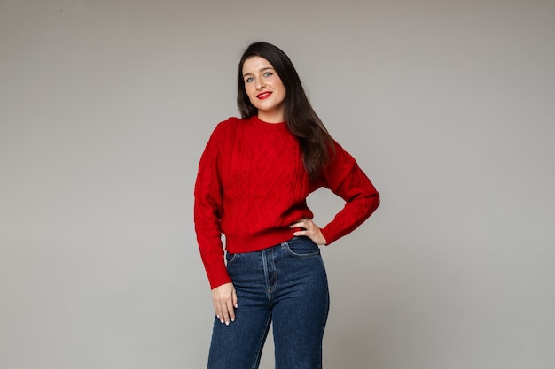 Жизнерадостная женщина в теплом красном свитере и синих джинсах