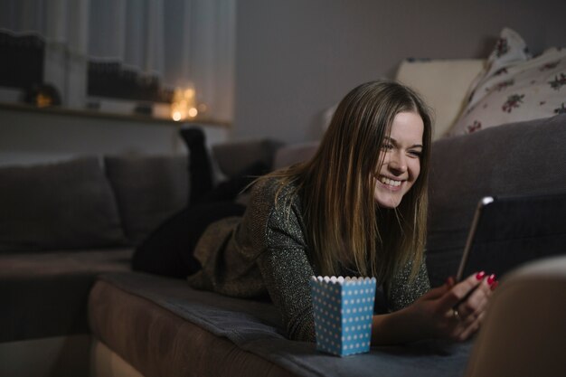 Веселая женщина смотрит фильм на планшете