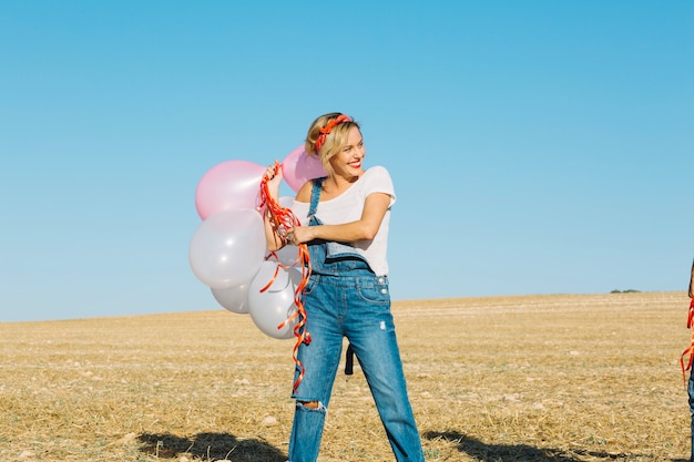 Веселая женщина с воздушными шарами в поле