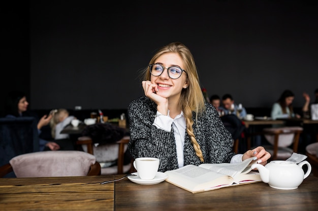 カフェでの本を持つ陽気な女性