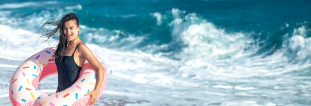 A cheerful woman with a doughnutshaped swimming circle by the sea