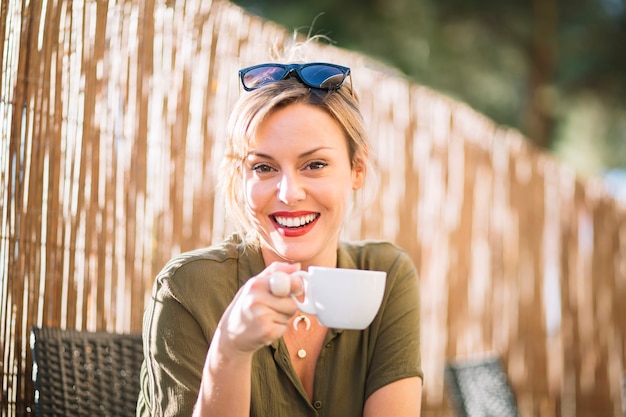 Cheerful woman with drink looking at camera