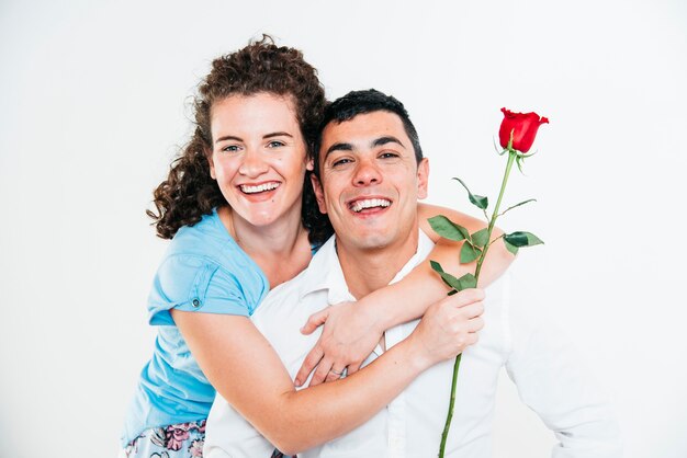 Cheerful woman with flower hugging smiling man