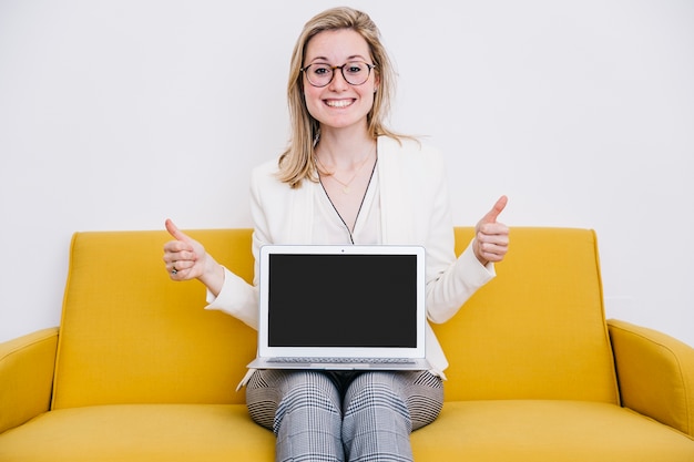 Cheerful woman with laptop gesturing thumb-up