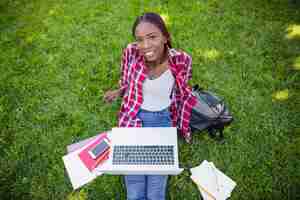 Free photo cheerful woman with laptop on grass