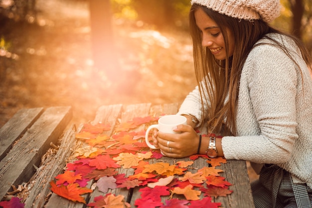 Cheerful woman with mug at table in autumn part