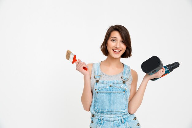 Cheerful woman with painting brush and hand drill