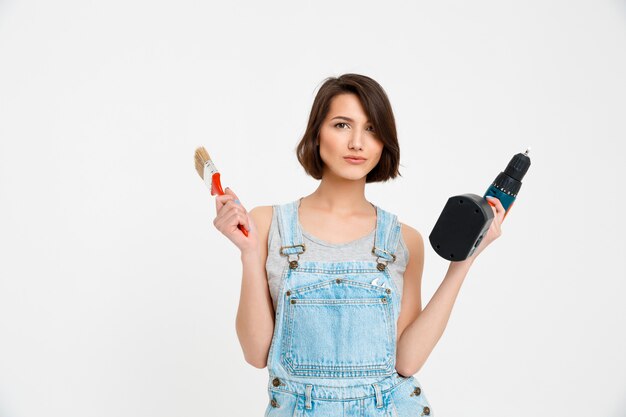 Cheerful woman with painting brush and hand drill