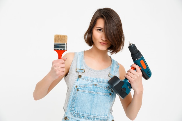 Free photo cheerful woman with painting brush and hand drill